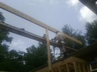Carpenter setting a ridge beam over a new addition frame — Ice Dam Removal by Roofing Brothers in Brownville