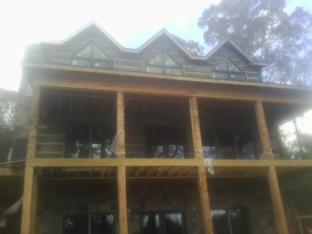 Dormers and porch framing on a large log home under construction — Roof Coating work by our crew in Brownville