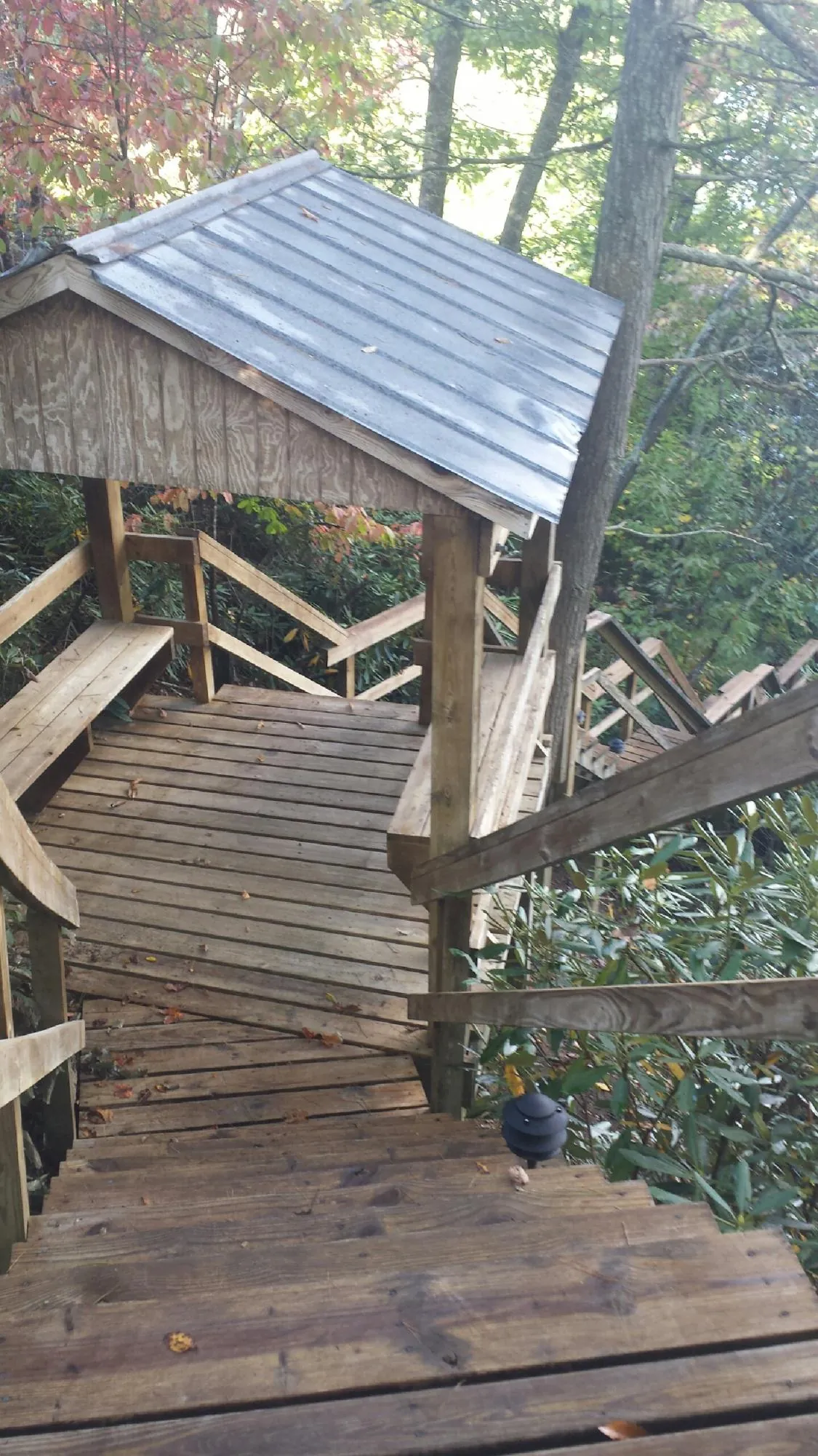 Metal roofed shelter over wooden steps on a wooded walkway — Skylight Repair & Installation work by our crew in Brownville