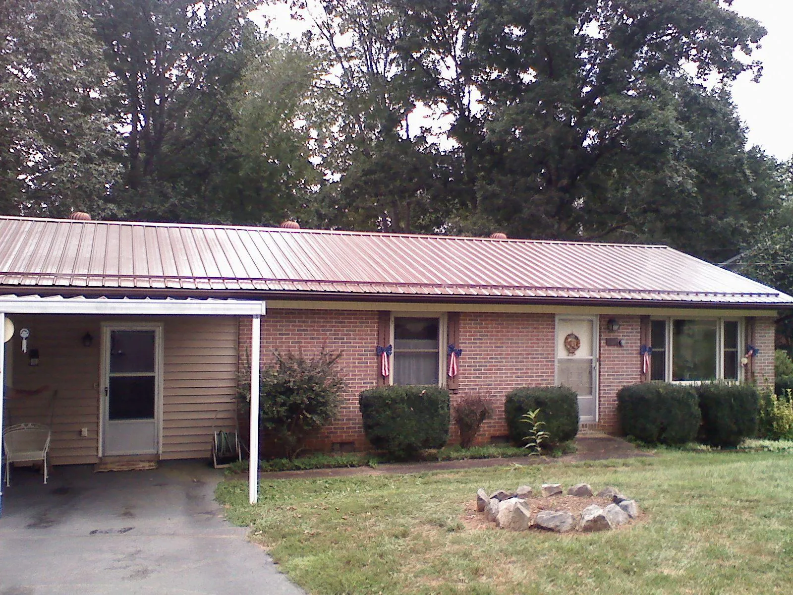 Bronze metal roof and carport on a brick ranch home — Roof Repair work by our crew in Brownville