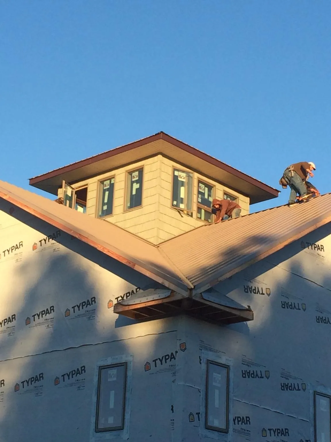 Roofers working around a rooftop cupola on a new metal roof at sunset — Roof Waterproofing in Brownville by Roofing Brothers